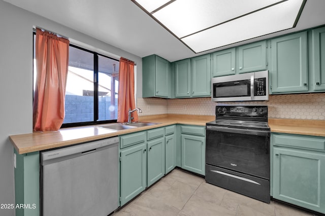 kitchen with sink, stainless steel appliances, tasteful backsplash, green cabinets, and light tile patterned floors