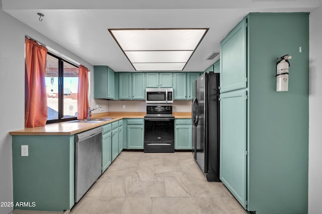 kitchen with kitchen peninsula, sink, tasteful backsplash, and black appliances