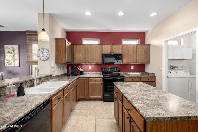 kitchen featuring sink, a center island, hanging light fixtures, black appliances, and washer and dryer