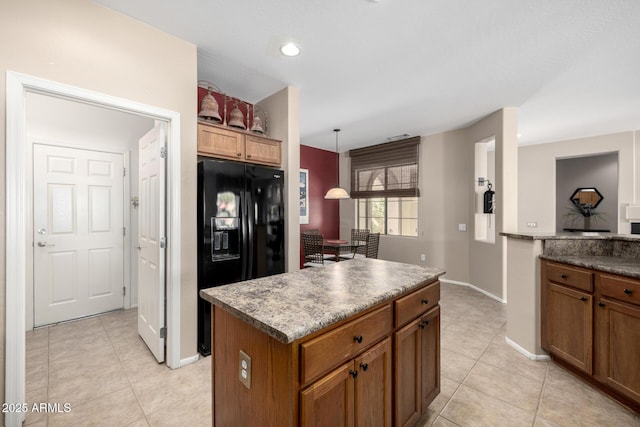 kitchen with black refrigerator with ice dispenser, a center island, light tile patterned floors, and pendant lighting