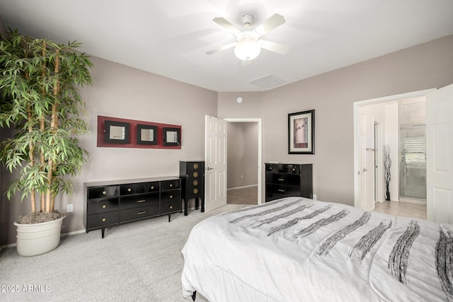 bedroom with ceiling fan, light colored carpet, and ensuite bathroom