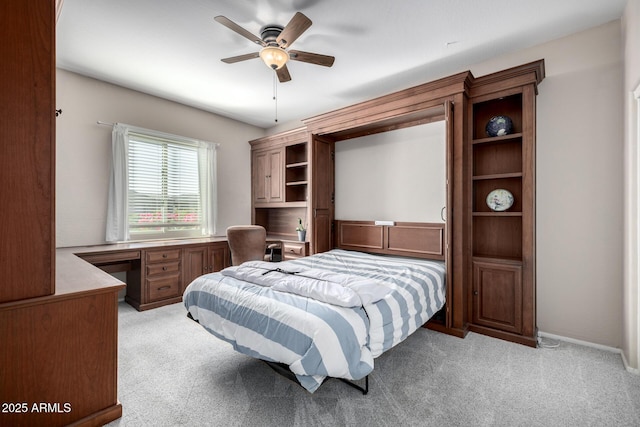 carpeted bedroom featuring built in desk and ceiling fan