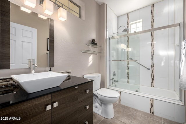 full bathroom featuring combined bath / shower with glass door, tile patterned floors, vanity, and toilet