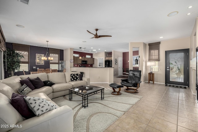 tiled living room with ceiling fan with notable chandelier