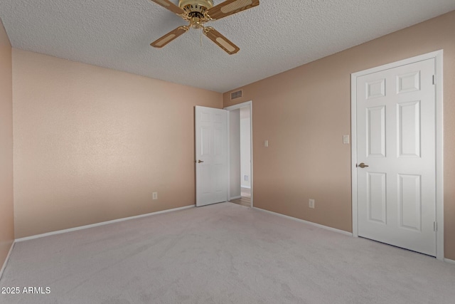 unfurnished bedroom featuring ceiling fan, light colored carpet, and a textured ceiling