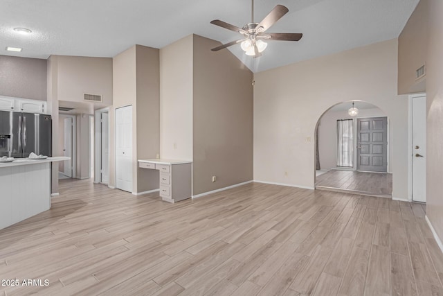 unfurnished living room with light hardwood / wood-style flooring, high vaulted ceiling, and ceiling fan