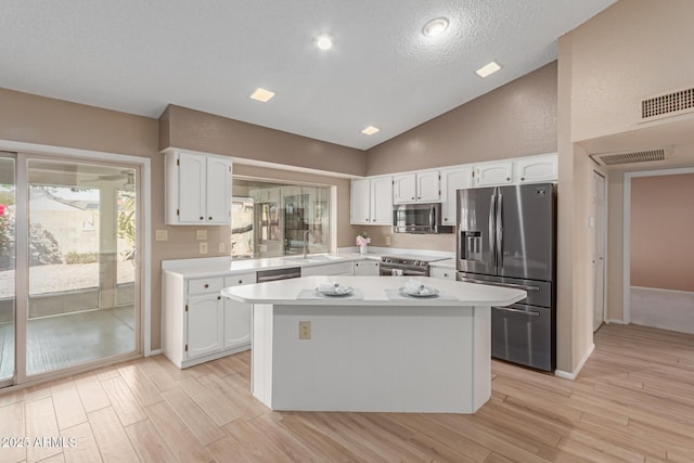 kitchen with sink, a center island, light wood-type flooring, appliances with stainless steel finishes, and white cabinets