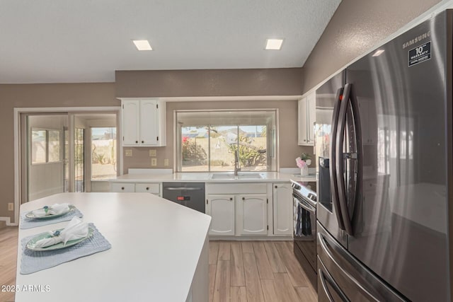 kitchen featuring sink, white cabinetry, light wood-type flooring, appliances with stainless steel finishes, and a healthy amount of sunlight