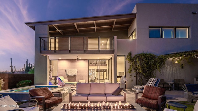6525 E Cave Creek Rd Unit 40, Cave Creek, AZ 85331 - back of house at dusk featuring a balcony, an outdoor living space with a fire pit, a patio, and stucco siding