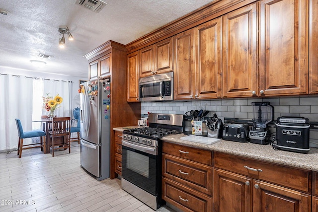 2022 W Aster Dr, Phoenix, AZ 85029 - kitchen with stainless steel appliances, brown cabinetry, decorative backsplash, a textured ceiling, and light stone counters