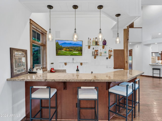 kitchen with lofted ceiling, light stone counters, wood finished floors, and pendant lighting