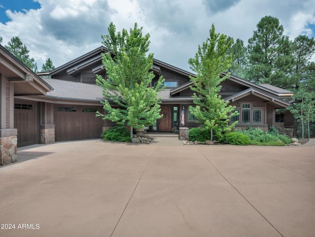 craftsman-style home featuring a garage, stone siding, and driveway