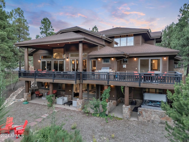 back of property featuring a shingled roof, outdoor lounge area, a patio area, a deck, and stone siding