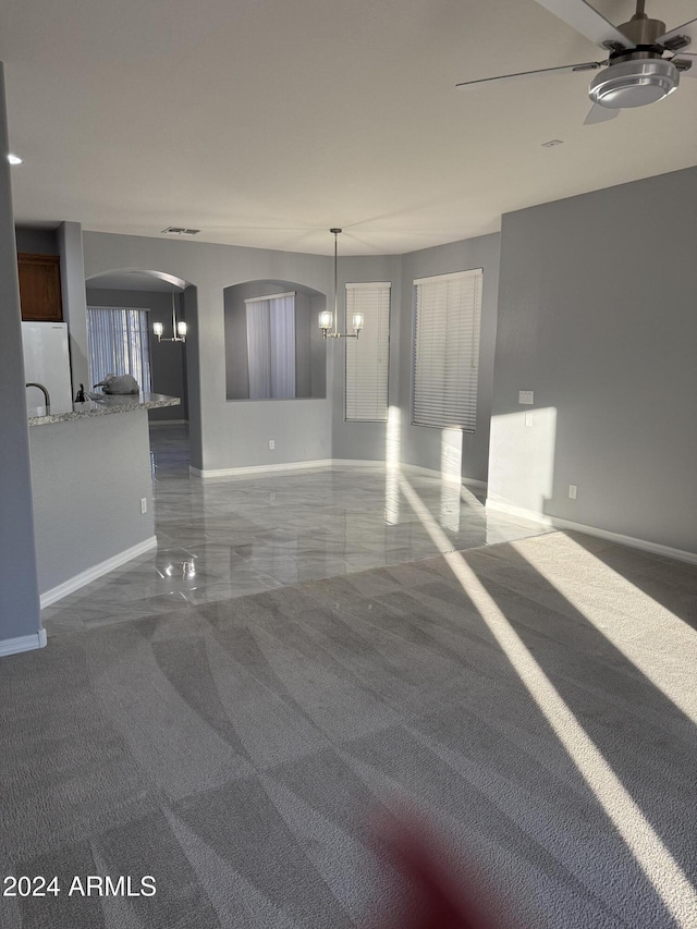 spare room with carpet and ceiling fan with notable chandelier