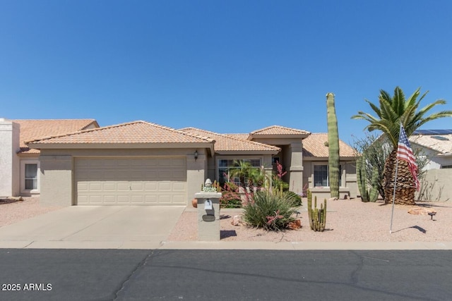 mediterranean / spanish-style house with a garage, concrete driveway, stucco siding, and a tiled roof