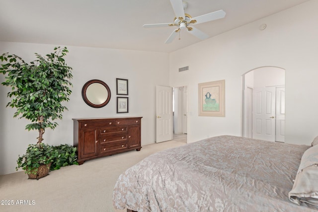 bedroom featuring light colored carpet, lofted ceiling, arched walkways, and ceiling fan