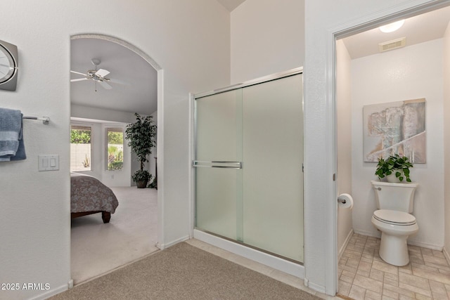 bathroom with ceiling fan, a shower stall, ensuite bathroom, toilet, and baseboards