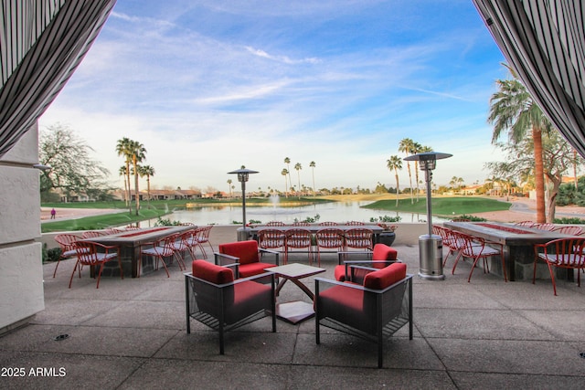 view of patio featuring a putting green, outdoor dining area, and a water view