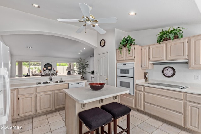 kitchen featuring a sink, light brown cabinets, arched walkways, light countertops, and recessed lighting