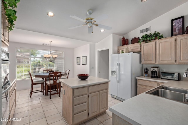 kitchen with white refrigerator with ice dispenser, light brown cabinetry, a sink, a kitchen island, and vaulted ceiling