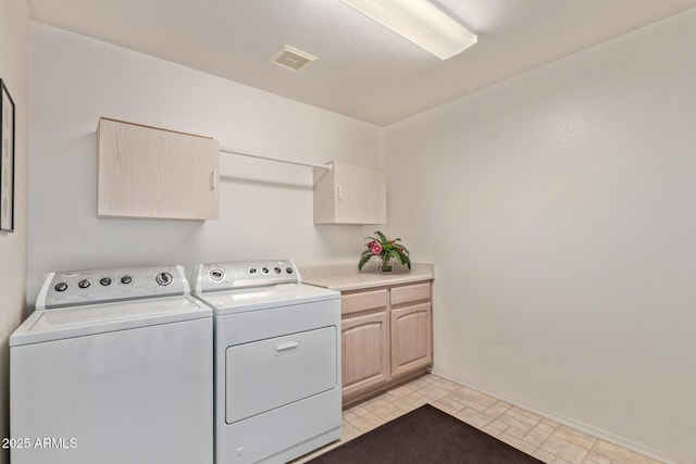 laundry area featuring separate washer and dryer, cabinet space, and baseboards