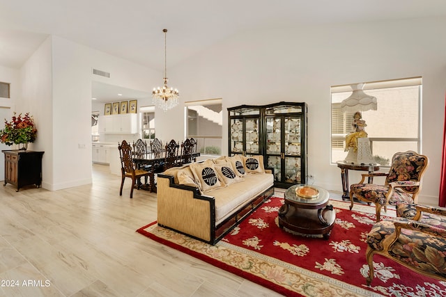 living room with light hardwood / wood-style flooring, an inviting chandelier, and high vaulted ceiling