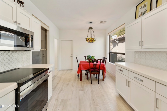 kitchen with decorative backsplash, white cabinets, stainless steel appliances, and pendant lighting