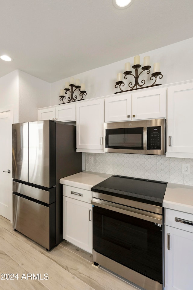 kitchen with appliances with stainless steel finishes, light hardwood / wood-style flooring, and white cabinetry