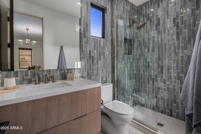 bathroom with tasteful backsplash, a notable chandelier, toilet, vanity, and tile walls