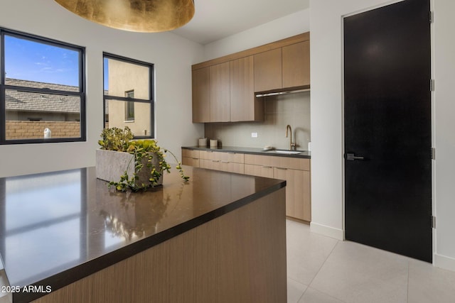 kitchen with light tile patterned flooring, backsplash, and sink