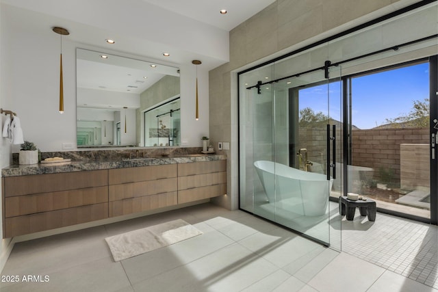 bathroom with a tub to relax in, tile patterned flooring, and vanity