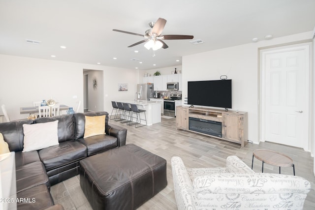 living room with light hardwood / wood-style floors and ceiling fan