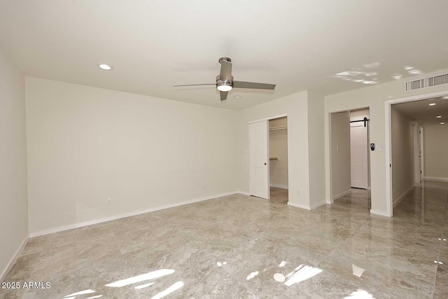 spare room featuring a barn door and ceiling fan