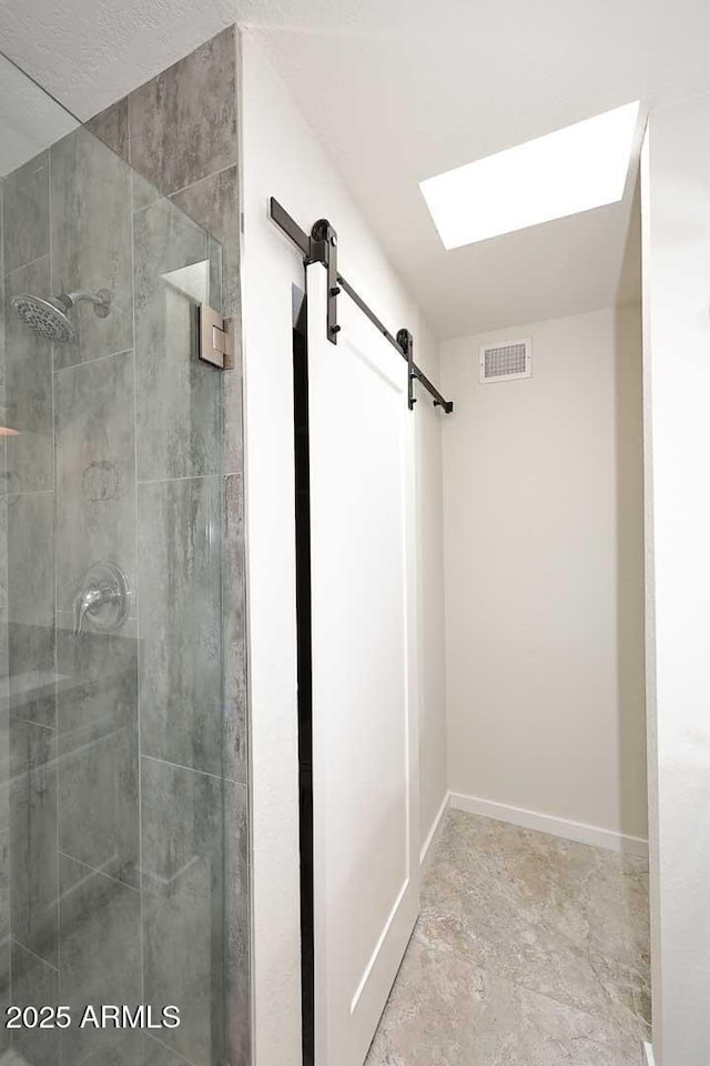 bathroom featuring a skylight and an enclosed shower