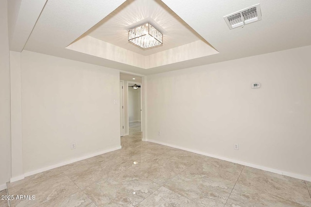 spare room with a tray ceiling and ceiling fan