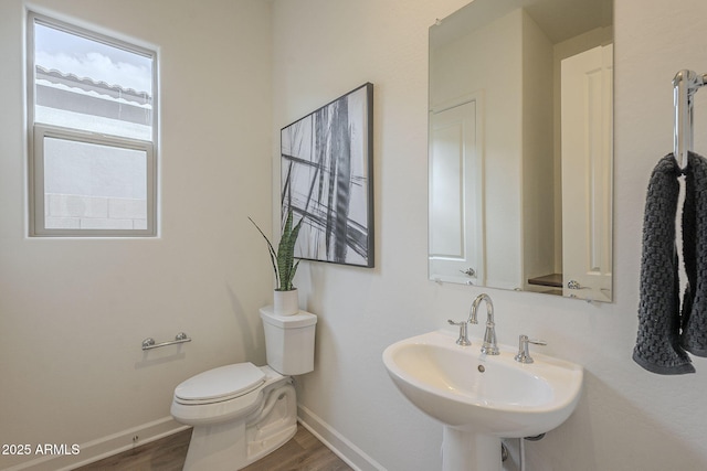 bathroom with a sink, baseboards, toilet, and wood finished floors