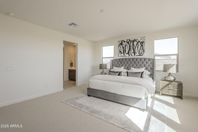 bedroom featuring visible vents, baseboards, light colored carpet, and connected bathroom