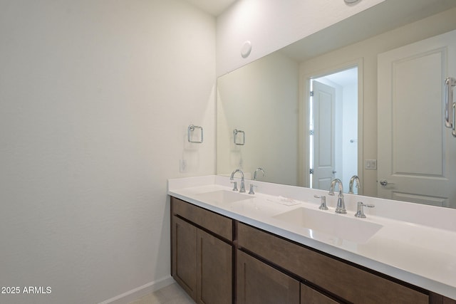 bathroom with double vanity, baseboards, and a sink