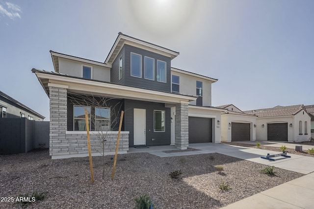 view of front facade featuring fence, driveway, an attached garage, covered porch, and stone siding