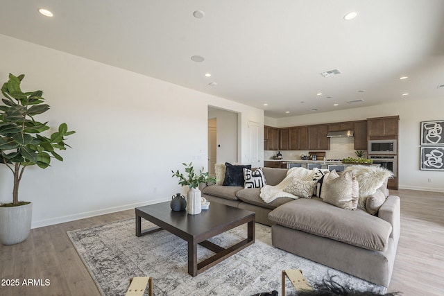 living room featuring recessed lighting, light wood-style floors, visible vents, and baseboards