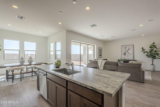 kitchen featuring open floor plan, visible vents, light wood finished floors, and a sink