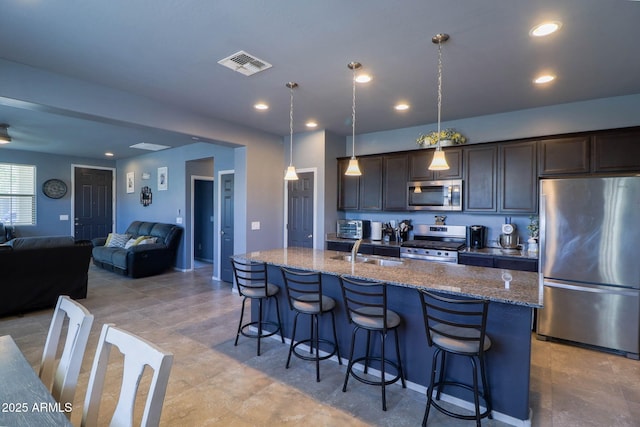 324 N 56th Pl, Mesa, AZ 85205 - kitchen featuring stainless steel appliances, a kitchen bar, light stone counters, a sink, and a center island with sink