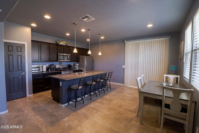 324 N 56th Pl, Mesa, AZ 85205 - kitchen with stainless steel appliances, a kitchen breakfast bar, dark brown cabinets, a center island with sink, and a sink