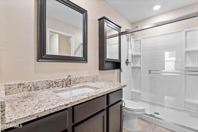 bathroom with tile patterned flooring, vanity, a shower with shower door, and toilet