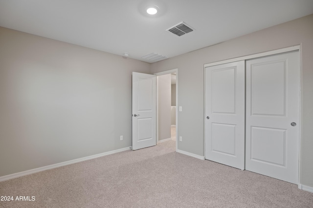 unfurnished bedroom with a closet and light carpet