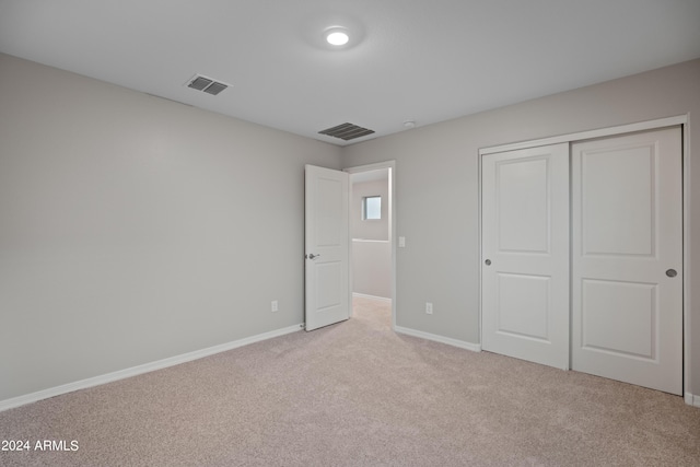 unfurnished bedroom with a closet and light carpet