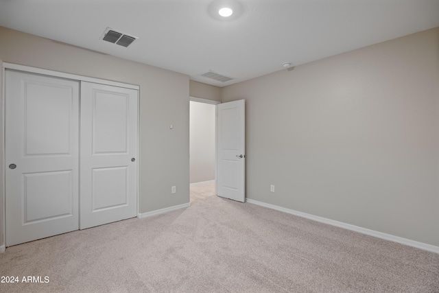 unfurnished bedroom with light colored carpet and a closet