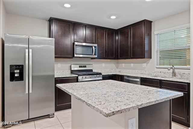 kitchen with sink, light tile patterned floors, a kitchen island, and appliances with stainless steel finishes