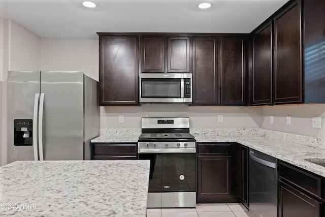 kitchen featuring dark brown cabinetry, appliances with stainless steel finishes, light stone countertops, and light tile patterned floors