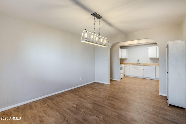 kitchen featuring white appliances, white cabinetry, sink, hanging light fixtures, and light wood-type flooring